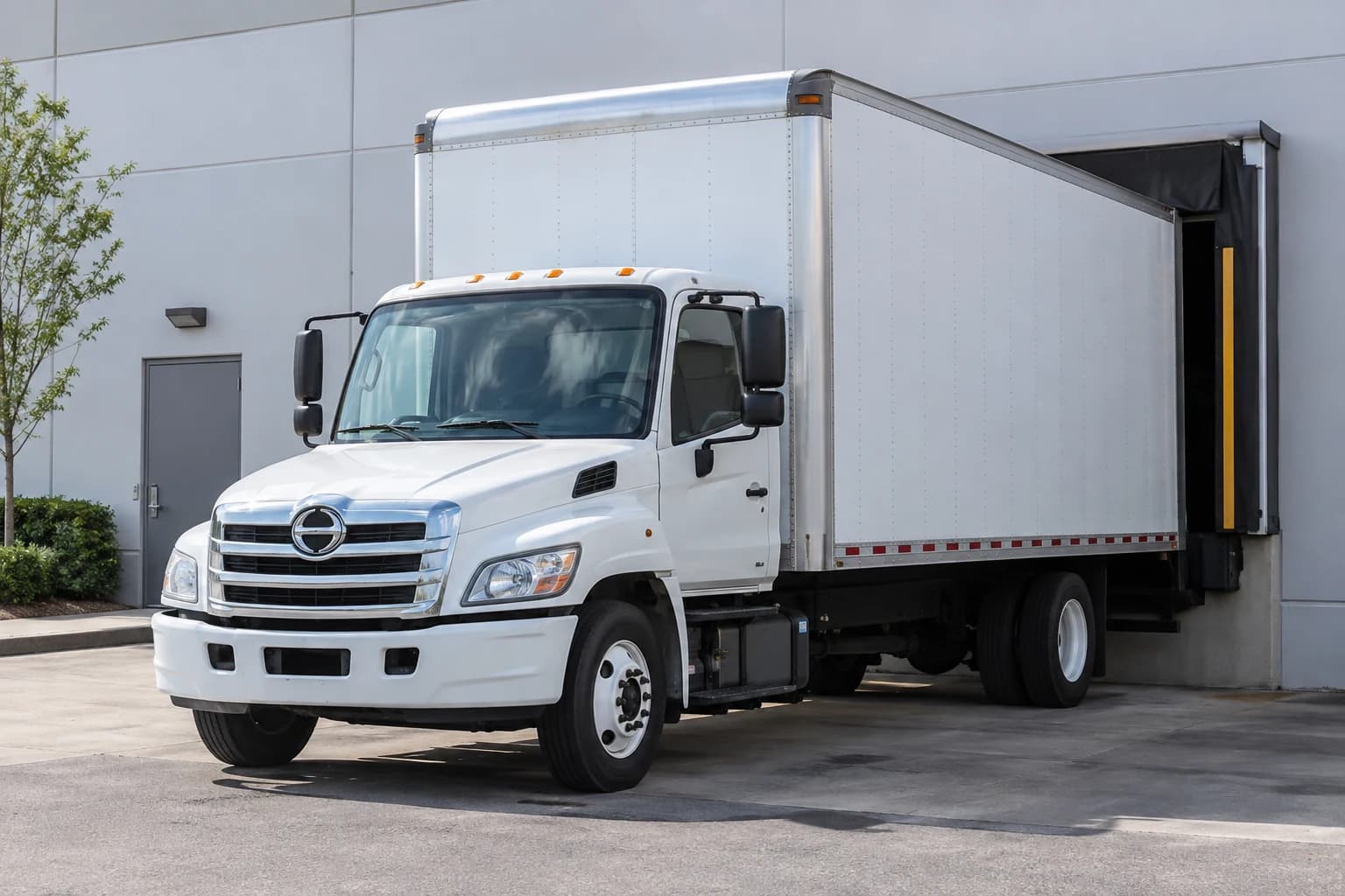 Illustrative scene of a white box truck at a warehouse loading dock